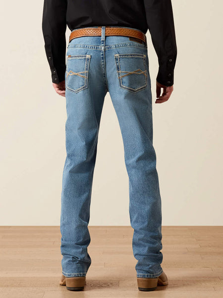 Rear view of a person wearing light blue denim jeans with a brown woven belt, black long-sleeve shirt, and brown boots against a beige studio background. If you need any assistance with this item or the purchase of this item please call us at five six one seven four eight eight eight zero one Monday through Saturday 10:00a.m EST to 8:00 p.m EST