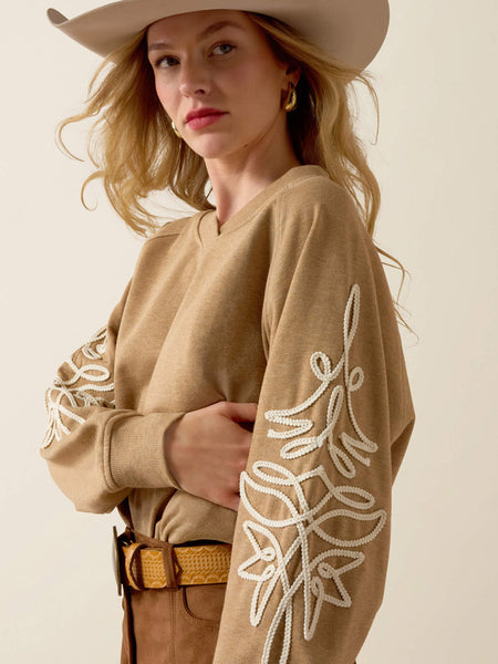 Ariat 10080602 Womens Juliette Sweatshirt Tan Heather sleeve view. If you need any assistance with this item or the purchase of this item please call us at five six one seven four eight eight eight zero one Monday through Saturday 10:00a.m EST to 8:00 p.m EST