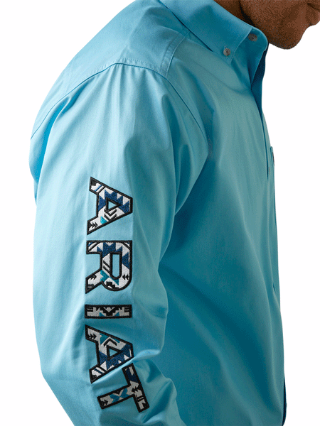 Ariat 10044940 Mens Team Logo Twill Classic Long Sleeve Shirt Cenote Aqua sleeve logo close up. If you need any assistance with this item or the purchase of this item please call us at five six one seven four eight eight eight zero one Monday through Saturday 10:00a.m EST to 8:00 p.m EST