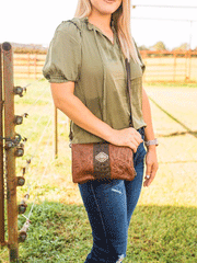 American West 7738078 Ladies Grab-and-Go Foldover Crossbody Brindle Hair-On Brown different color on model to show crossbody style. If you need any assistance with this item or the purchase of this item please call us at five six one seven four eight eight eight zero one Monday through Saturday 10:00a.m EST to 8:00 p.m EST