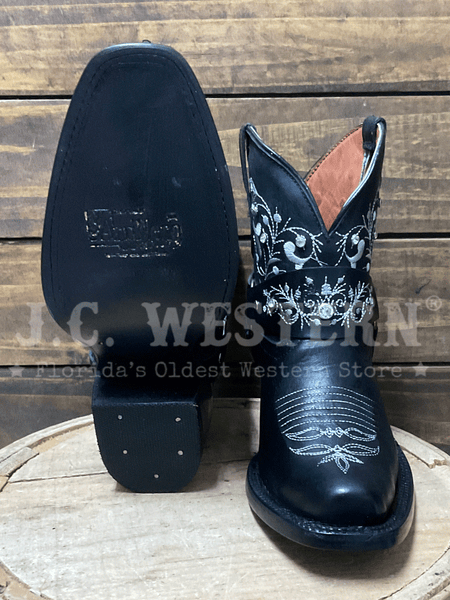 Black cowboy boots with white embroidery on a wooden surface, front and sole view. If you need any assistance with this item or the purchase of this item please call us at five six one seven four eight eight eight zero one Monday through Saturday 10:00a.m EST to 8:00 p.m EST