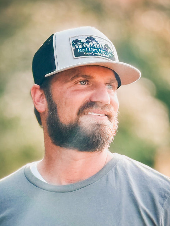 Red Dirt RDHC-461 SNIPE HUNTING Trucker Cap Black And Silver on model. If you need any assistance with this item or the purchase of this item please call us at five six one seven four eight eight eight zero one Monday through Saturday 10:00a.m EST to 8:00 p.m EST