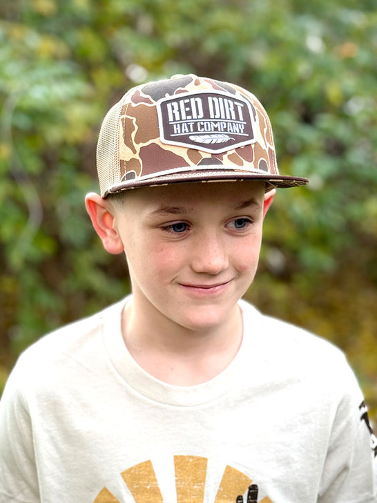 Red Dirt RDHCY-55 OLD SKOOL Youth Trucker Cap Camo Tan on model. If you need any assistance with this item or the purchase of this item please call us at five six one seven four eight eight eight zero one Monday through Saturday 10:00a.m EST to 8:00 p.m EST
