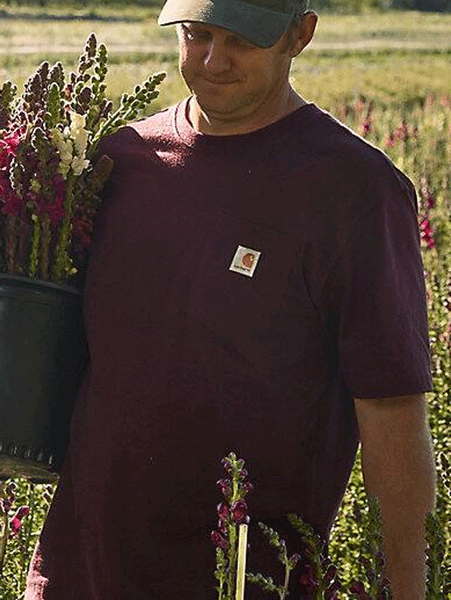 Carhartt K87-PRT Mens Loose Fit Heavyweight Short Sleeve Pocket T-Shirt Port on model outdoors. If you need any assistance with this item or the purchase of this item please call us at five six one seven four eight eight eight zero one Monday through Saturday 10:00a.m EST to 8:00 p.m EST