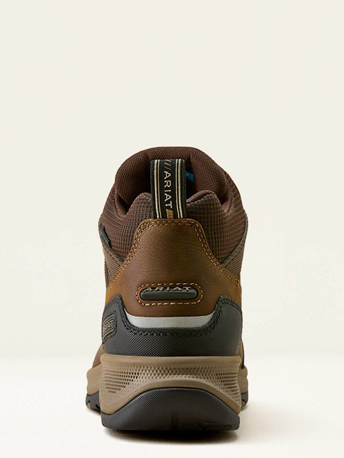 A brown mid-cut hiking boot with a black and tan sole, shown from a three-quarters angle against a light beige background. If you need any assistance with this item or the purchase of this item please call us at five six one seven four eight eight eight zero one Monday through Saturday 10:00a.m EST to 8:00 p.m EST
