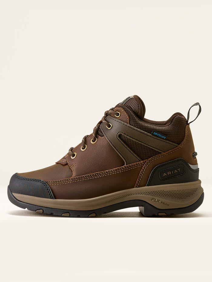 A brown mid-cut hiking boot with a black and tan sole, shown from a three-quarters angle against a light beige background. If you need any assistance with this item or the purchase of this item please call us at five six one seven four eight eight eight zero one Monday through Saturday 10:00a.m EST to 8:00 p.m EST