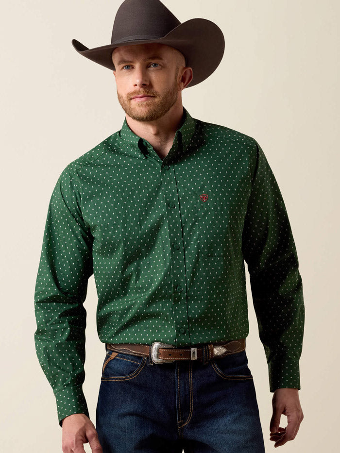 A man wearing a dark green long-sleeve button-down shirt with a small white polka dot pattern, paired with blue jeans and a dark brown cowboy hat, against a solid beige background. If you need any assistance with this item or the purchase of this item please call us at five six one seven four eight eight eight zero one Monday through Saturday 10:00a.m EST to 8:00 p.m EST