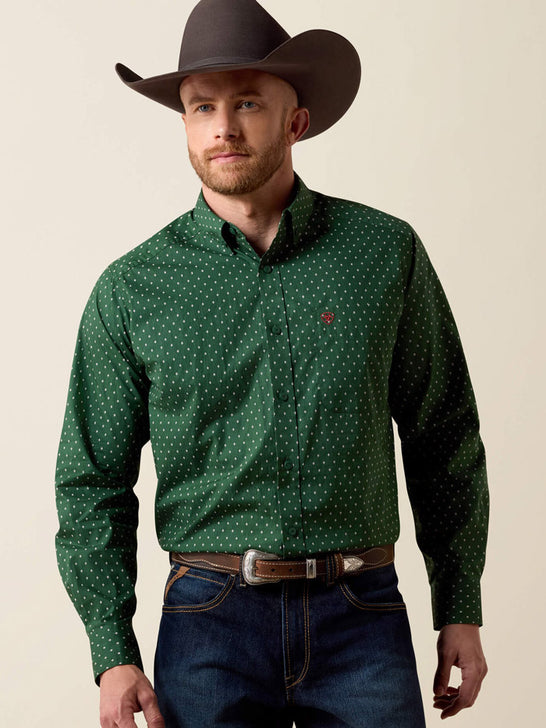 A man wearing a dark green long-sleeve button-down shirt with a small white polka dot pattern, paired with blue jeans and a dark brown cowboy hat, against a solid beige background. If you need any assistance with this item or the purchase of this item please call us at five six one seven four eight eight eight zero one Monday through Saturday 10:00a.m EST to 8:00 p.m EST