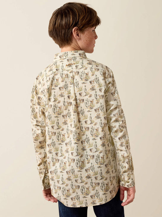 A child model shown from the back wearing a cream-colored long-sleeve button-up shirt with a detailed brown and beige illustrated pattern, paired with dark blue jeans, against a plain beige background. If you need any assistance with this item or the purchase of this item please call us at five six one seven four eight eight eight zero one Monday through Saturday 10:00a.m EST to 8:00 p.m EST