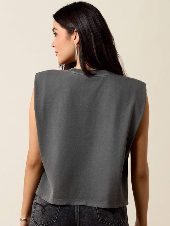 A woman shown from the back wearing a dark gray sleeveless crop top and dark jeans, photographed against a plain light beige studio background. If you need any assistance with this item or the purchase of this item please call us at five six one seven four eight eight eight zero one Monday through Saturday 10:00a.m EST to 8:00 p.m EST