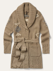 A beige knit cardigan with a shawl collar, matching tie belt, and decorative geometric patterns in cream and blue on the sleeves, shown flat against a light off-white background. If you need any assistance with this item or the purchase of this item please call us at five six one seven four eight eight eight zero one Monday through Saturday 10:00a.m EST to 8:00 p.m EST