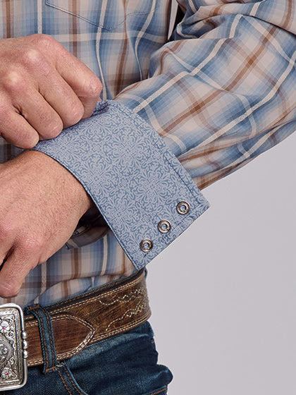 Close-up of a man's hands adjusting the cuff of a light blue patterned western shirt, worn with a brown leather belt and blue jeans. If you need any assistance with this item or the purchase of this item please call us at five six one seven four eight eight eight zero one Monday through Saturday 10:00a.m EST to 8:00 p.m EST