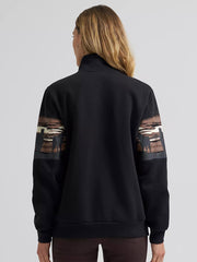 A woman viewed from the back wearing a black quarter-zip sweatshirt with brown and beige graphic panels on the upper sleeves, paired with dark brown pants, against a light gray studio background. If you need any assistance with this item or the purchase of this item please call us at five six one seven four eight eight eight zero one Monday through Saturday 10:00a.m EST to 8:00 p.m EST