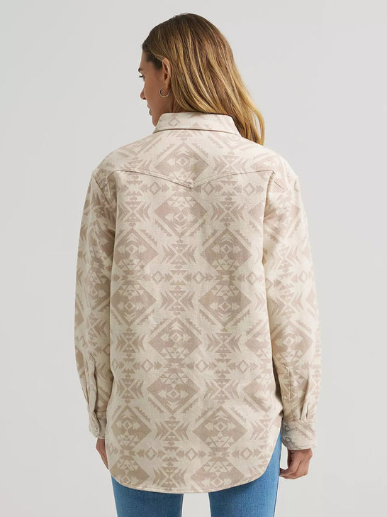 A woman shown from the back wearing a long-sleeve button-up shirt with a beige and cream geometric pattern, paired with blue jeans, against a light gray studio background. If you need any assistance with this item or the purchase of this item please call us at five six one seven four eight eight eight zero one Monday through Saturday 10:00a.m EST to 8:00 p.m EST