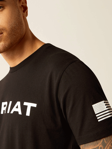 Ariat 10054197 Mens Shield Flag T-Shirt Black side close up view. If you need any assistance with this item or the purchase of this item please call us at five six one seven four eight eight eight zero one Monday through Saturday 10:00a.m EST to 8:00 p.m EST