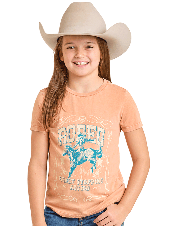 Young girl wearing a peach t-shirt with a rodeo graphic and a cowboy hat on a white background front view. If you need any assistance with this item or the purchase of this item please call us at five six one seven four eight eight eight zero one Monday through Saturday 10:00a.m EST to 8:00 p.m EST