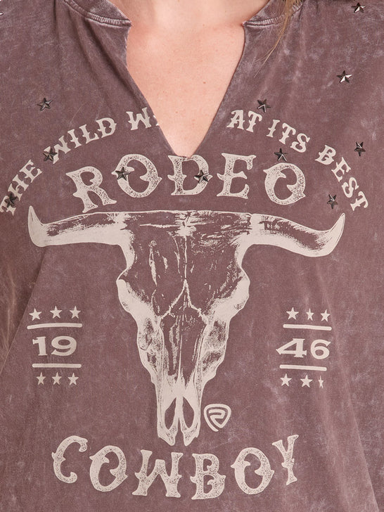 Close-up of a person wearing a distressed brown V-neck t-shirt with a western 'Rodeo Cowboy' graphic featuring a bull skull and stars. If you need any assistance with this item or the purchase of this item please call us at five six one seven four eight eight eight zero one Monday through Saturday 10:00a.m EST to 8:00 p.m EST