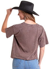A woman shown from the back wearing a washed brown short-sleeve t-shirt and blue jeans, while adjusting a black cowboy hat against a plain white background. If you need any assistance with this item or the purchase of this item please call us at five six one seven four eight eight eight zero one Monday through Saturday 10:00a.m EST to 8:00 p.m EST