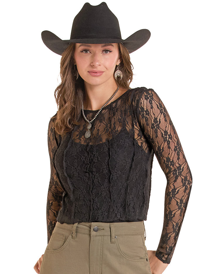 A woman wearing a black long-sleeve lace top with sheer sleeves, a black cowboy hat, and khaki pants, photographed against a plain white background. If you need any assistance with this item or the purchase of this item please call us at five six one seven four eight eight eight zero one Monday through Saturday 10:00a.m EST to 8:00 p.m EST
