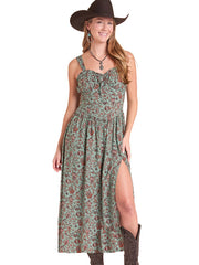 A woman modeling a sleeveless midi dress with a green and rust floral pattern, a smocked bodice, and a high side slit. She is also wearing a dark brown cowboy hat and boots against a plain white background. If you need any assistance with this item or the purchase of this item please call us at five six one seven four eight eight eight zero one Monday through Saturday 10:00a.m EST to 8:00 p.m EST