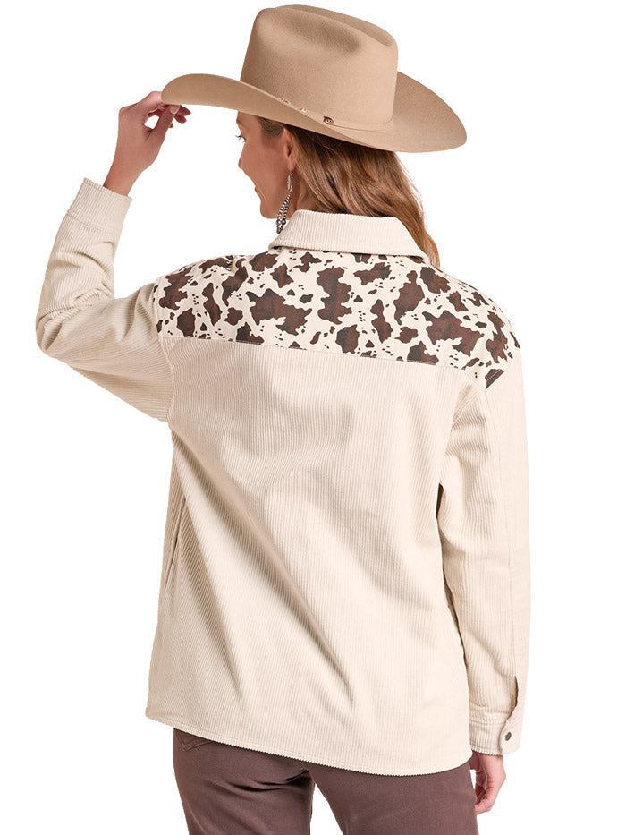A woman wearing a beige western-style button-up shirt with brown and cream cow-print chest panels, paired with a tan cowboy hat, brown top, and brown pants, against a plain white background. If you need any assistance with this item or the purchase of this item please call us at five six one seven four eight eight eight zero one Monday through Saturday 10:00a.m EST to 8:00 p.m EST