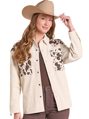 A woman wearing a beige western-style button-up shirt with brown and cream cow-print chest panels, paired with a tan cowboy hat, brown top, and brown pants, against a plain white background. If you need any assistance with this item or the purchase of this item please call us at five six one seven four eight eight eight zero one Monday through Saturday 10:00a.m EST to 8:00 p.m EST