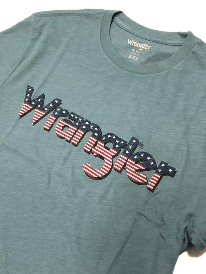 Wrangler 112336214 Mens American Flag Logo T-Shirt Medium Blue front view on model. If you need any assistance with this item or the purchase of this item please call us at five six one seven four eight eight eight zero one Monday through Saturday 10:00a.m EST to 8:00 p.m EST