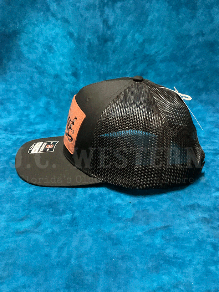 Ariat A300086201 Faux Leather Patch Cap Black front and side view. If you need any assistance with this item or the purchase of this item please call us at five six one seven four eight eight eight zero one Monday through Saturday 10:00a.m EST to 8:00 p.m EST