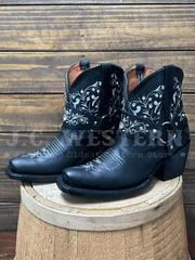 Black cowboy boots with white embroidery on a wooden barrel against a wooden background side view. If you need any assistance with this item or the purchase of this item please call us at five six one seven four eight eight eight zero one Monday through Saturday 10:00a.m EST to 8:00 p.m EST