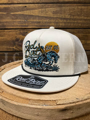 An off-white trucker hat with a mesh back, featuring a graphic of a cowboy on a blue horse and the text 'Red Dirt HAT CO.' on the front.If you need any assistance with this item or the purchase of this item please call us at five six one seven four eight eight eight zero one Monday through Saturday 10:00a.m EST to 8:00 p.m EST