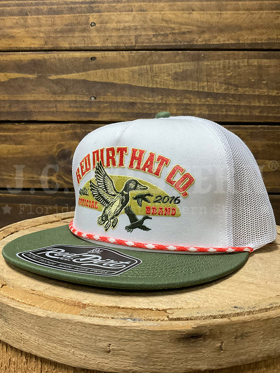 A white and olive green trucker hat with a duck graphic on the front, displayed on a rustic wooden stump against a wood plank background.If you need any assistance with this item or the purchase of this item please call us at five six one seven four eight eight eight zero one Monday through Saturday 10:00a.m EST to 8:00 p.m EST