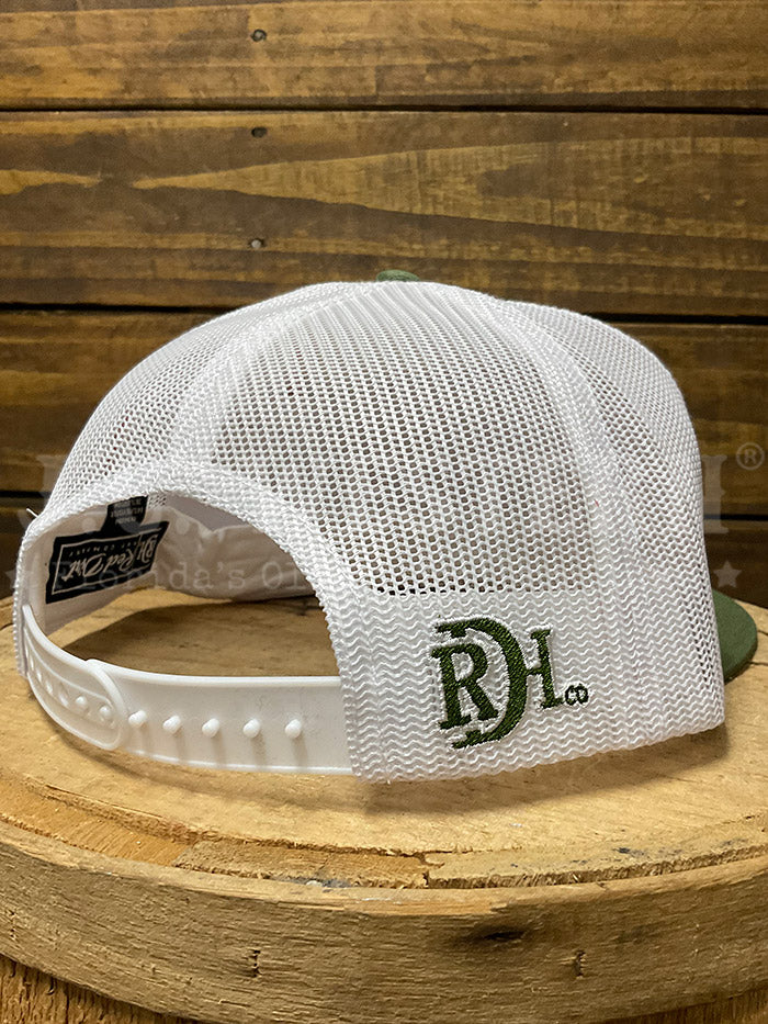 A white and olive green trucker hat with a duck graphic on the front, displayed on a rustic wooden stump against a wood plank background.If you need any assistance with this item or the purchase of this item please call us at five six one seven four eight eight eight zero one Monday through Saturday 10:00a.m EST to 8:00 p.m EST