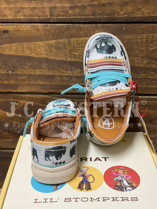 A pair of Ariat Lil' Stompers western-style sneakers with buffalo prints, turquoise laces, and orange accents, displayed on top of their branded box against a rustic wooden background. If you need any assistance with this item or the purchase of this item please call us at five six one seven four eight eight eight zero one Monday through Saturday 10:00a.m EST to 8:00 p.m EST