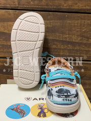 A pair of children's western-style sneakers shown on a wooden surface, with one shoe standing upright to display the sole and the other lying down to show the patterned upper. The shoes feature turquoise laces, a cream sole, and a multicolor western print with black silhouettes and orange, red, blue, and white accents. If you need any assistance with this item or the purchase of this item please call us at five six one seven four eight eight eight zero one Monday through Saturday 10:00a.m EST to 8:00 p.m ES