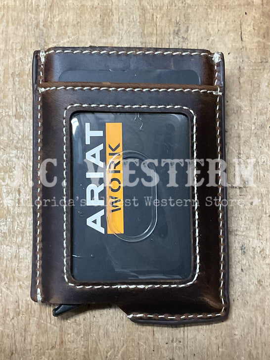 A dark brown leather card holder wallet with white contrast stitching, featuring a clear ID window displaying an 'Ariat Work' card. The wallet is photographed flat on a light brown wooden surface, with a semi-transparent 'Cactus Western' watermark overlay. If you need any assistance with this item or the purchase of this item please call us at five six one seven four eight eight eight zero one Monday through Saturday 10:00a.m EST to 8:00 p.m EST