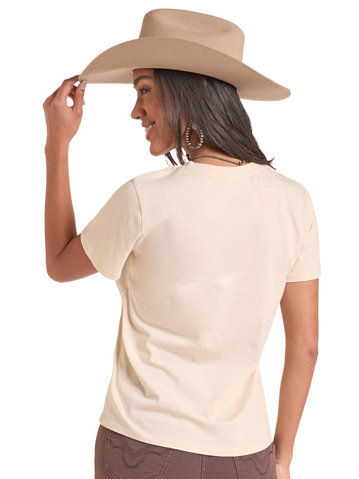 A woman wearing a beige cowboy hat and a cream-colored graphic t-shirt with 'Buckle Up Country' and 'Life's a Rider' printed on the front, set against a plain white background. If you need any assistance with this item or the purchase of this item please call us at five six one seven four eight eight eight zero one Monday through Saturday 10:00a.m EST to 8:00 p.m EST