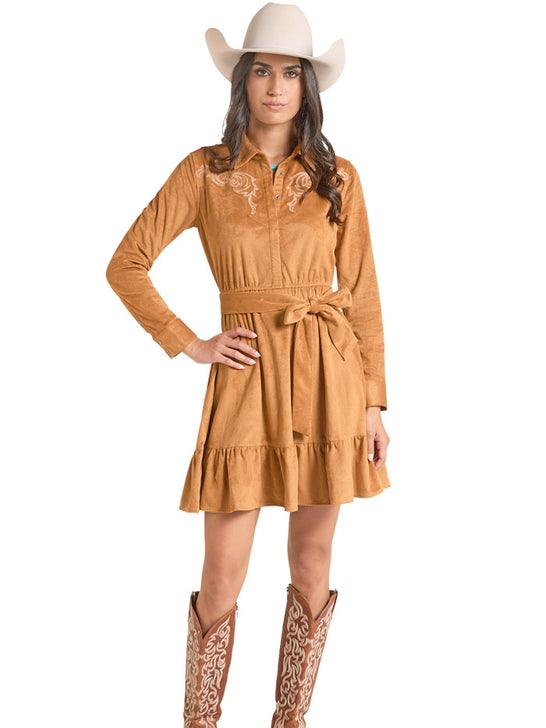 A woman modeling a tan faux-suede western dress with embroidered detailing on the chest, a matching tie belt, and a ruffled hem, styled with a white cowboy hat and brown cowboy boots against a white background. If you need any assistance with this item or the purchase of this item please call us at five six one seven four eight eight eight zero one Monday through Saturday 10:00a.m EST to 8:00 p.m EST