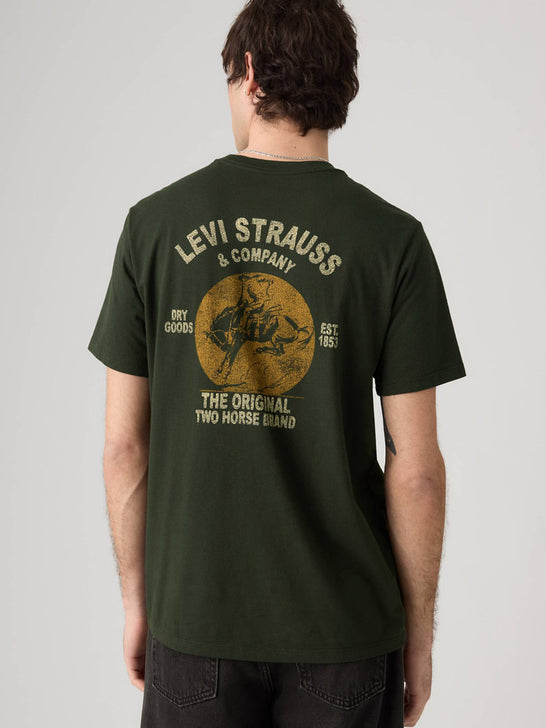 A man viewed from the back wearing an olive green Levi's t-shirt with a large vintage-style graphic on the back in beige and brown. If you need any assistance with this item or the purchase of this item please call us at five six one seven four eight eight eight zero one Monday through Saturday 10:00a.m EST to 8:00 p.m EST