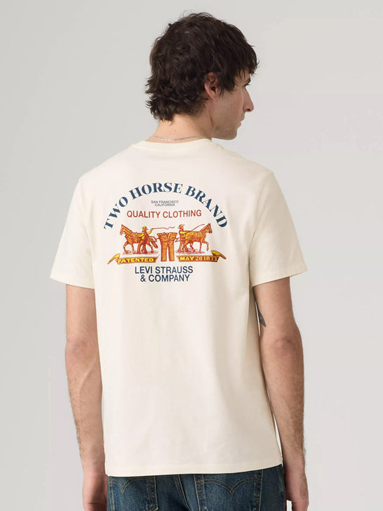 A man wearing a cream-colored Levi's t-shirt, viewed from the back. The shirt features a large graphic print with the text 'TWO HORSE BRAND' and 'LEVI STRAUSS & COMPANY' in blue, along with an orange illustration of a carriage and horses. If you need any assistance with this item or the purchase of this item please call us at five six one seven four eight eight eight zero one Monday through Saturday 10:00a.m EST to 8:00 p.m EST
