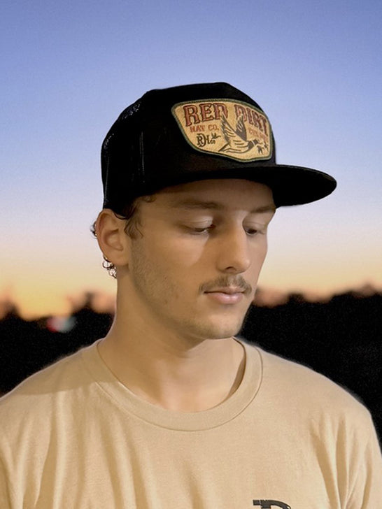 Red Dirt RDHC-488 FLY SOUTH Trucker Cap Black on model. If you need any assistance with this item or the purchase of this item please call us at five six one seven four eight eight eight zero one Monday through Saturday 10:00a.m EST to 8:00 p.m EST