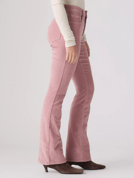 A model shown from the waist down wearing dusty pink flared jeans, a cream long-sleeve top, and brown pointed-toe heeled boots against a light gray studio background. If you need any assistance with this item or the purchase of this item please call us at five six one seven four eight eight eight zero one Monday through Saturday 10:00a.m EST to 8:00 p.m EST