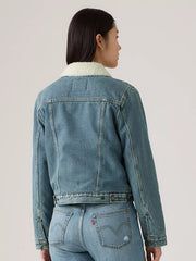 A model shown from the back wearing a light blue denim jacket with a white sherpa collar, paired with matching light blue denim jeans against a plain light gray studio background. If you need any assistance with this item or the purchase of this item please call us at five six one seven four eight eight eight zero one Monday through Saturday 10:00a.m EST to 8:00 p.m EST