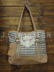 CatchFly 2164600TAN Womens Floral Cow Skull Suede Fringe Tote Tan on display hanging. If you need any assistance with this item or the purchase of this item please call us at five six one seven four eight eight eight zero one Monday through Saturday 10:00a.m EST to 8:00 p.m EST