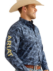 Ariat 10048393 Mens Team Garett Classic Fit Shirt Blue sleeve logo view. If you need any assistance with this item or the purchase of this item please call us at five six one seven four eight eight eight zero one Monday through Saturday 10:00a.m EST to 8:00 p.m EST
