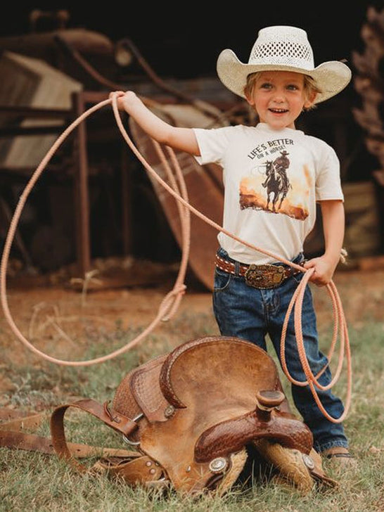 Shea Baby BVINB08 Kids Lifes Better On A Horse Shirt Beige front view on model. If you need any assistance with this item or the purchase of this item please call us at five six one seven four eight eight eight zero one Monday through Saturday 10:00a.m EST to 8:00 p.m EST