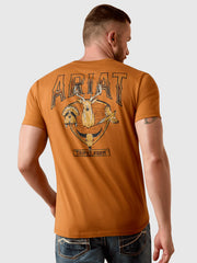 A man wearing a burnt orange t-shirt from the back, featuring a large graphic print with the word 'ARIAT' and a trophy design. The shirt is shown on a model against a light gray background. If you need any assistance with this item or the purchase of this item please call us at five six one seven four eight eight eight zero one Monday through Saturday 10:00a.m EST to 8:00 p.m EST