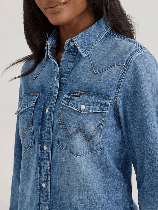 Wrangler 112360739 Womens Classic Denim Slim Western Snap Shirt Mid Wash front close up. If you need any assistance with this item or the purchase of this item please call us at five six one seven four eight eight eight zero one Monday through Saturday 10:00a.m EST to 8:00 p.m EST