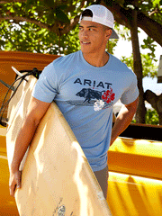 Ariat 10044013 Mens SurfBoarding Western Aloha T-Shirt Light Blue Heather on model outdoors. If you need any assistance with this item or the purchase of this item please call us at five six one seven four eight eight eight zero one Monday through Saturday 10:00a.m EST to 8:00 p.m EST