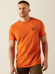 Ariat 10054774 Mens Barb Shield T-Shirt Rust front view.If you need any assistance with this item or the purchase of this item please call us at five six one seven four eight eight eight zero one Monday through Saturday 10:00a.m EST to 8:00 p.m EST